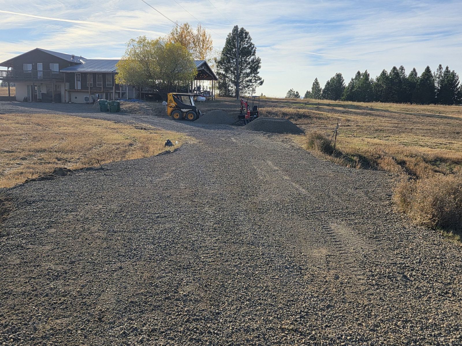 New gravel driveway with a High Mountain skidsteer and mini excavator on site